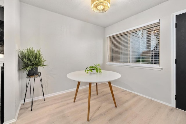 dining space featuring baseboards and light wood-type flooring