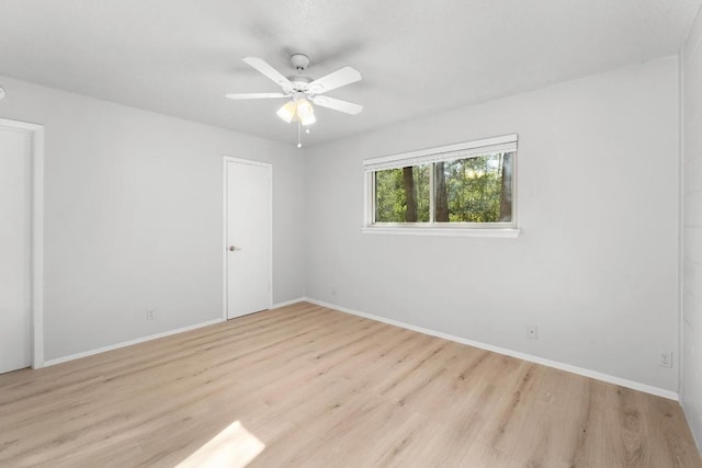 empty room featuring wood finished floors, baseboards, and ceiling fan