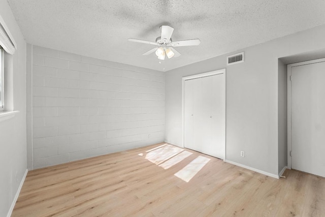 unfurnished bedroom featuring visible vents, a textured ceiling, a closet, and wood finished floors