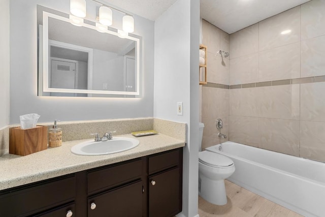 full bath featuring shower / bathing tub combination, toilet, wood finished floors, and vanity