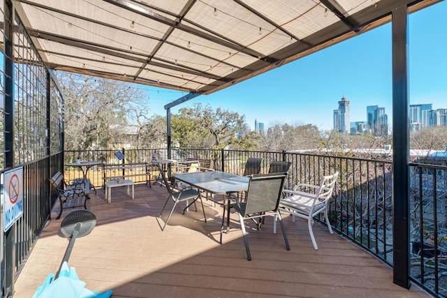 wooden deck with a city view and outdoor dining space