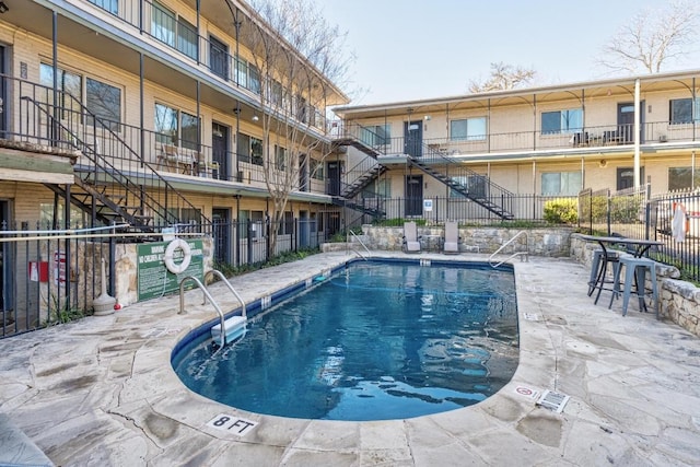 view of pool with stairway and fence