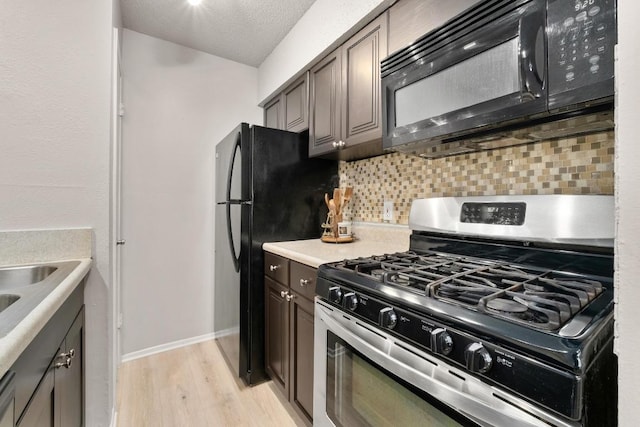 kitchen with decorative backsplash, black appliances, light countertops, a textured ceiling, and light wood-type flooring