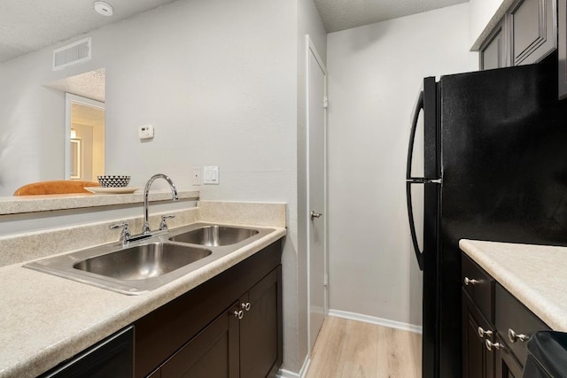 kitchen with black appliances, light countertops, visible vents, and a sink