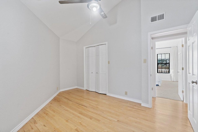 unfurnished bedroom featuring high vaulted ceiling, baseboards, visible vents, and light wood-type flooring