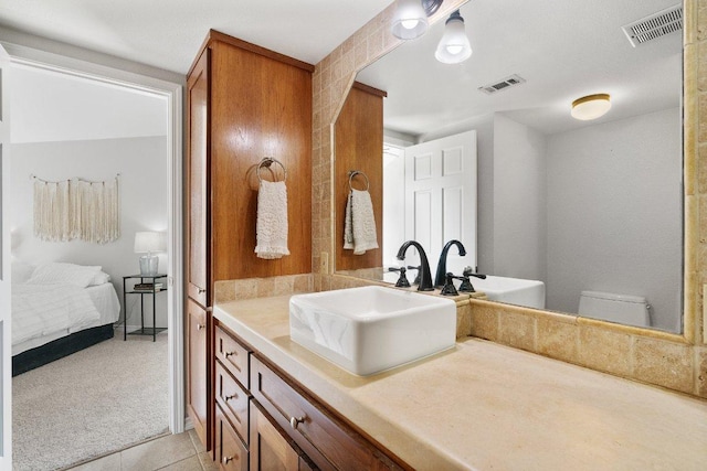 ensuite bathroom with tile patterned floors, visible vents, connected bathroom, and vanity