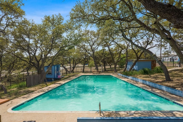 view of swimming pool with a fenced backyard and an outdoor structure