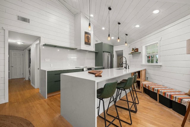 kitchen with visible vents, light wood-type flooring, a kitchen breakfast bar, high quality fridge, and a sink