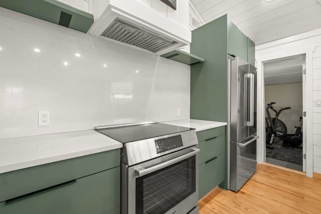 kitchen with ventilation hood, stainless steel appliances, green cabinets, and light countertops