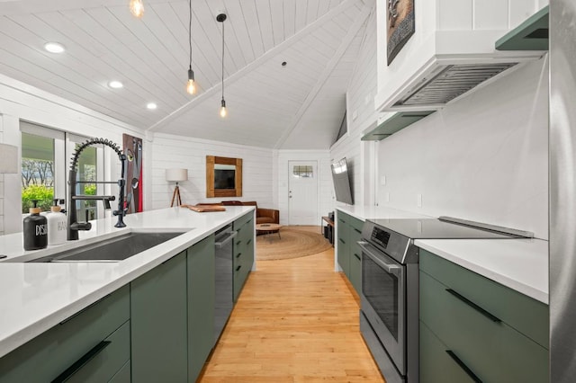 kitchen with light wood finished floors, green cabinetry, lofted ceiling with beams, a sink, and stainless steel appliances