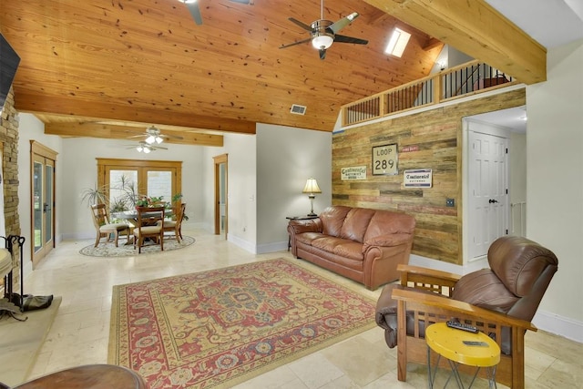 living room with visible vents, beamed ceiling, wooden ceiling, ceiling fan, and an accent wall