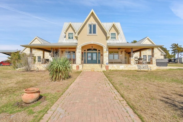 view of front facade with a porch, stucco siding, french doors, and metal roof