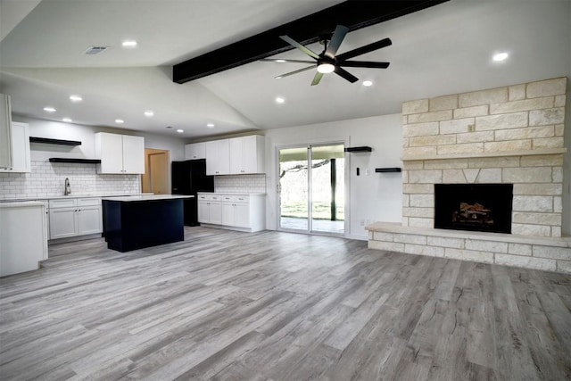 kitchen with open shelves, lofted ceiling with beams, a sink, open floor plan, and freestanding refrigerator