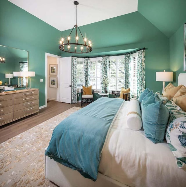 bedroom featuring baseboards, a notable chandelier, wood finished floors, and vaulted ceiling