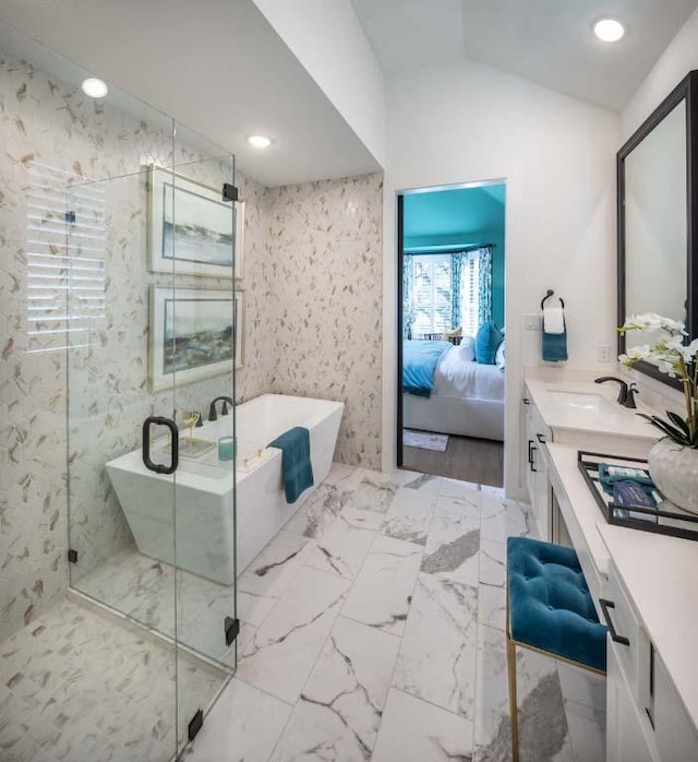 ensuite bathroom with connected bathroom, a freestanding bath, vaulted ceiling, marble finish floor, and vanity