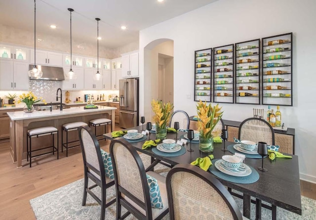 dining space featuring arched walkways, recessed lighting, and light wood-type flooring