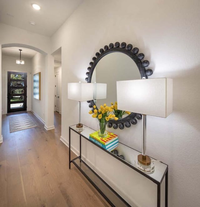 entrance foyer featuring arched walkways, baseboards, and wood finished floors