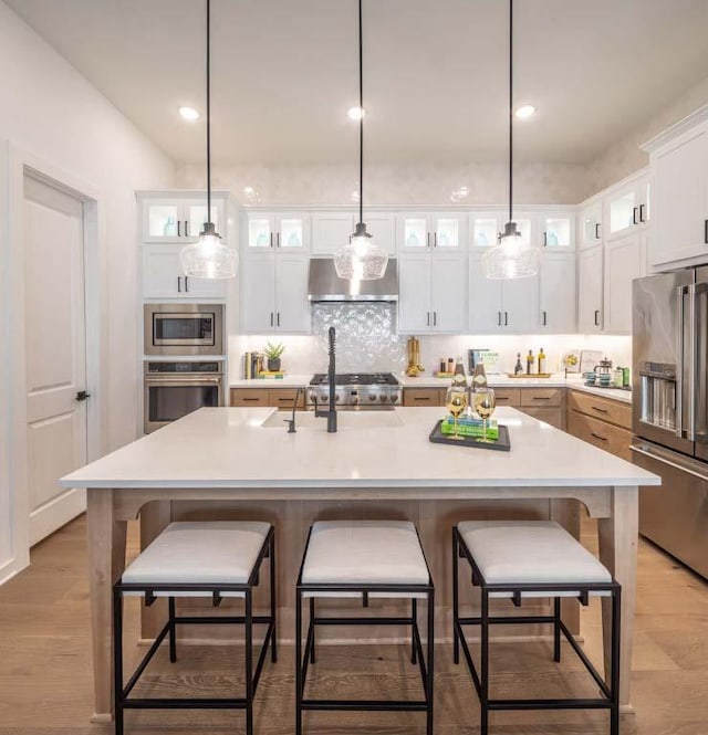 kitchen featuring ventilation hood, light countertops, appliances with stainless steel finishes, white cabinetry, and tasteful backsplash