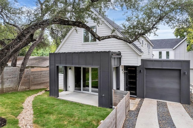 view of front of property with board and batten siding, an attached garage, and fence