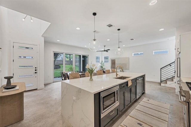 kitchen featuring a kitchen island with sink, decorative light fixtures, recessed lighting, stainless steel appliances, and concrete flooring