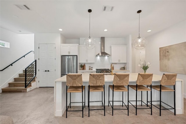 3100 S 5th St Unit 1, Austin, TX 78704 - kitchen with wall chimney exhaust hood, stainless steel refrigerator, white cabinetry, a breakfast bar area, and a spacious island