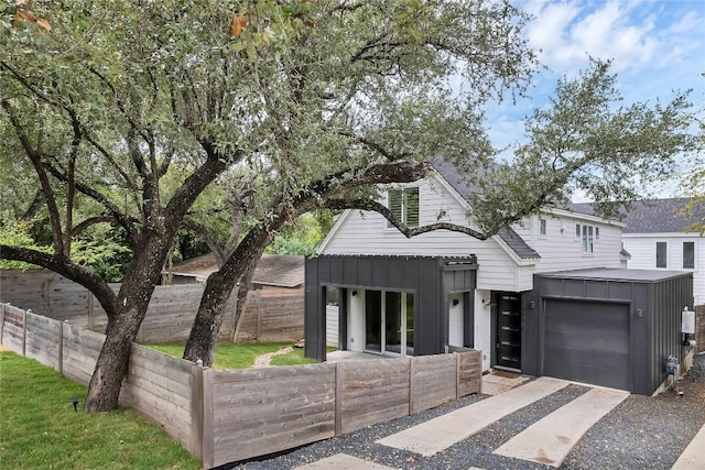 view of front facade with concrete driveway, board and batten siding, and roof with shingles