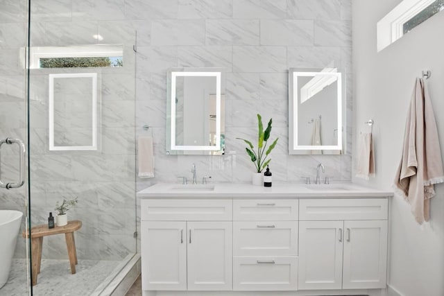 full bath with decorative backsplash, double vanity, a stall shower, and a sink