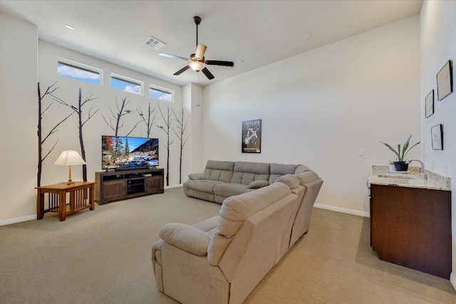 living area with visible vents, light colored carpet, a ceiling fan, and baseboards