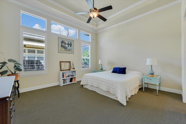 bedroom featuring baseboards, a tray ceiling, ceiling fan, crown molding, and dark carpet