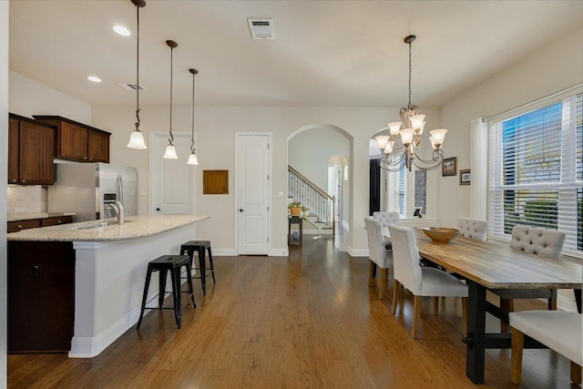 dining room featuring dark wood-style floors, baseboards, visible vents, arched walkways, and stairs