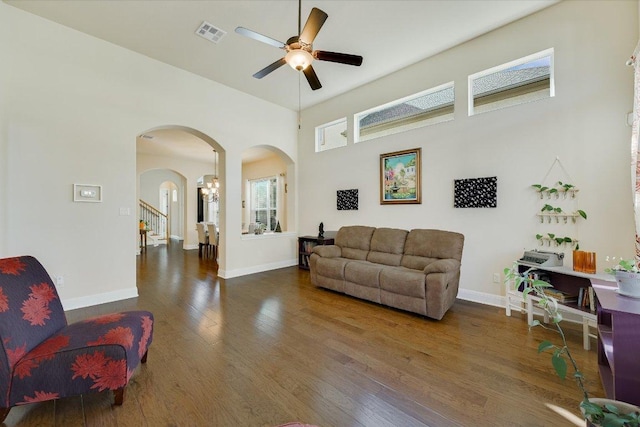 living room featuring visible vents, baseboards, arched walkways, and wood finished floors