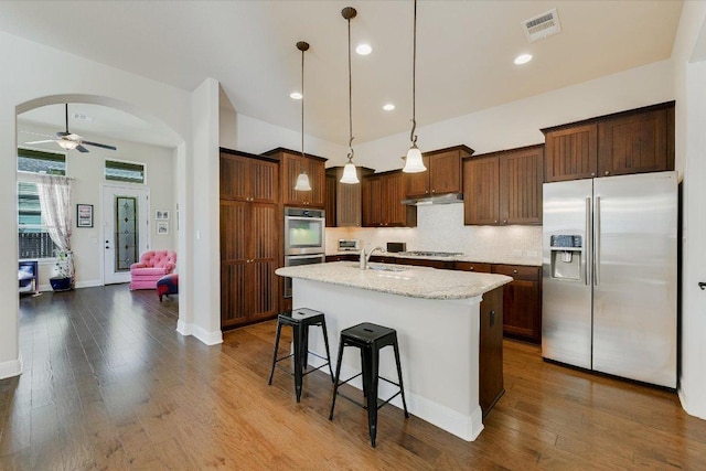 kitchen with visible vents, dark wood finished floors, arched walkways, a sink, and stainless steel appliances