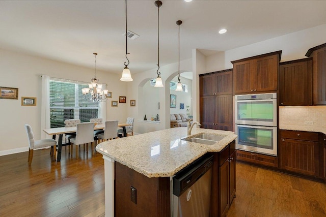 kitchen featuring visible vents, dark wood-type flooring, a sink, arched walkways, and appliances with stainless steel finishes