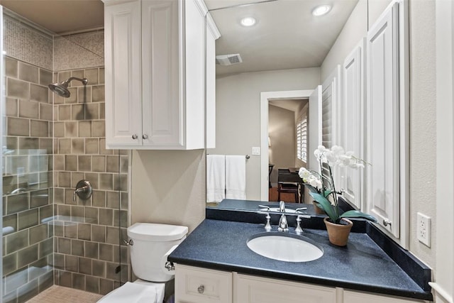 bathroom featuring vanity, visible vents, recessed lighting, a tile shower, and toilet