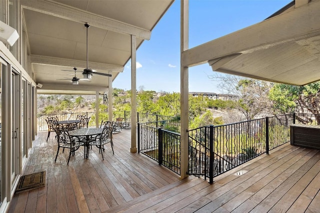 wooden terrace with outdoor dining space and a ceiling fan