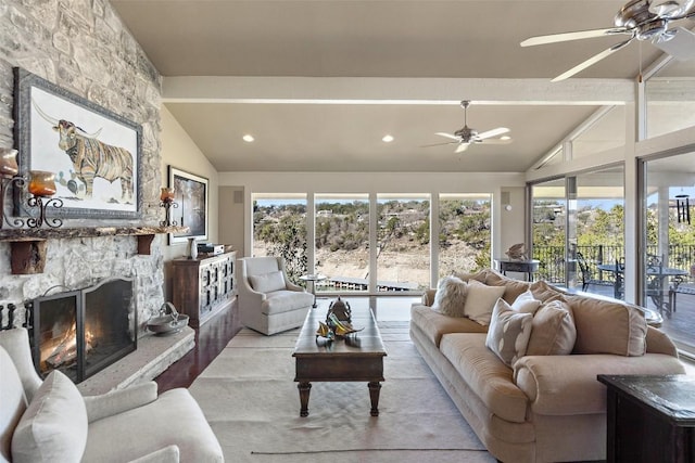 living room featuring a stone fireplace, vaulted ceiling with beams, and ceiling fan