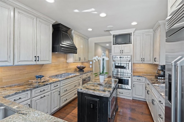 kitchen with light stone counters, dark wood-style floors, appliances with stainless steel finishes, custom exhaust hood, and white cabinetry