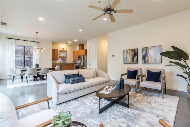 living room featuring recessed lighting, ceiling fan with notable chandelier, and baseboards