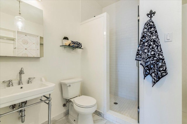 bathroom featuring baseboards, toilet, marble finish floor, and a tile shower