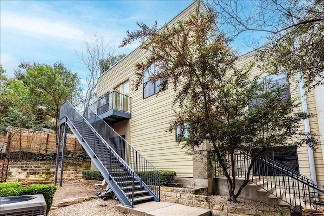 back of property featuring stairway, a balcony, and central AC