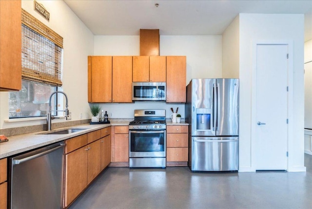 kitchen featuring concrete floors, light countertops, appliances with stainless steel finishes, brown cabinetry, and a sink