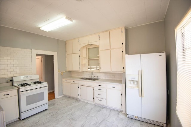 kitchen with a sink, white appliances, marble finish floor, and light countertops