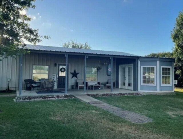 616 S Rockdale St, Lexington, TX 78947 - rear view of house featuring board and batten siding, french doors, a lawn, and metal roof