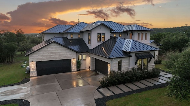 view of front of home with metal roof, stone siding, a garage, and a standing seam roof