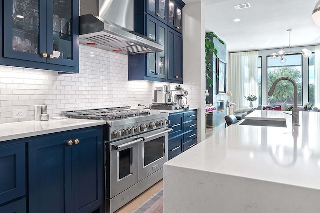 714 Crystal Creek Dr, Austin, TX 78746 - kitchen featuring range with two ovens, wall chimney range hood, blue cabinets, decorative backsplash, and recessed lighting