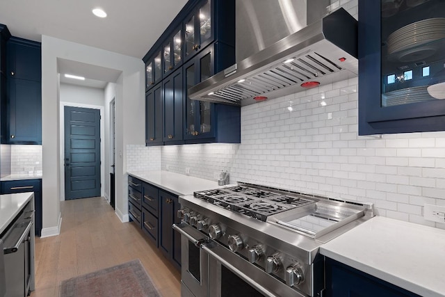 714 Crystal Creek Dr, Austin, TX 78746 - kitchen with wall chimney exhaust hood, double oven range, tasteful backsplash, blue cabinets, and recessed lighting