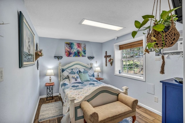 bedroom featuring baseboards, a textured ceiling, and wood finished floors