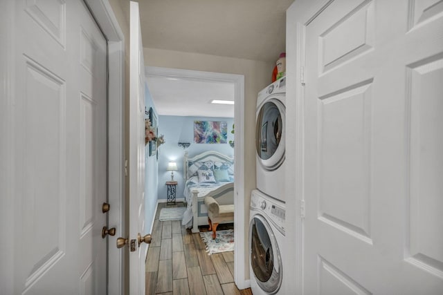 clothes washing area with stacked washer / drying machine, laundry area, and light wood finished floors