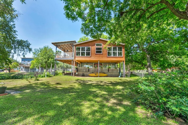 rear view of house with a wooden deck, a yard, and fence