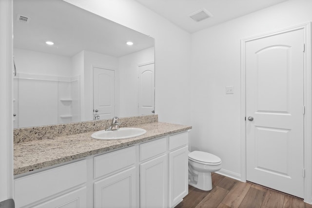 bathroom with visible vents, toilet, wood finished floors, baseboards, and vanity